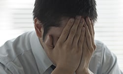 Male with both hands covering his face in frustration